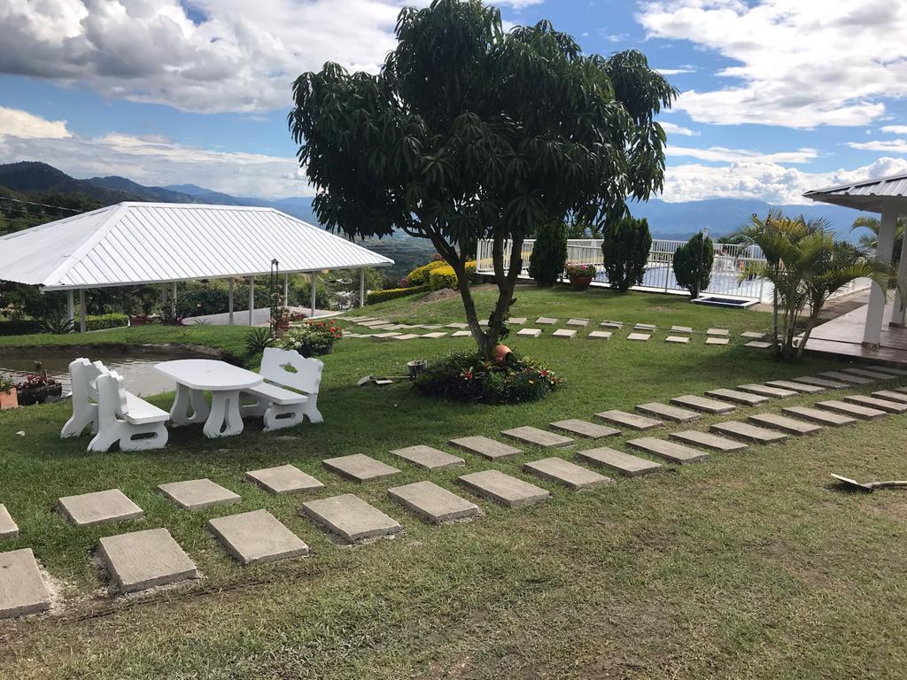 Mesa blanca junto al kiosco con la piscina y las montañas de fondo
