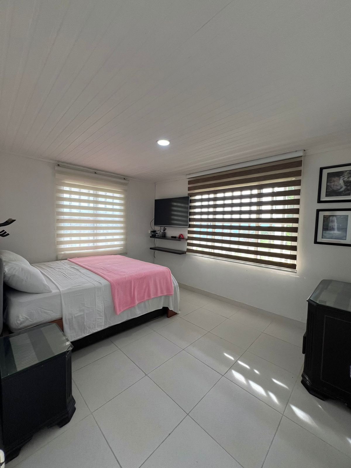 Habitación principal con cama doble, TV y cortinas enrollables